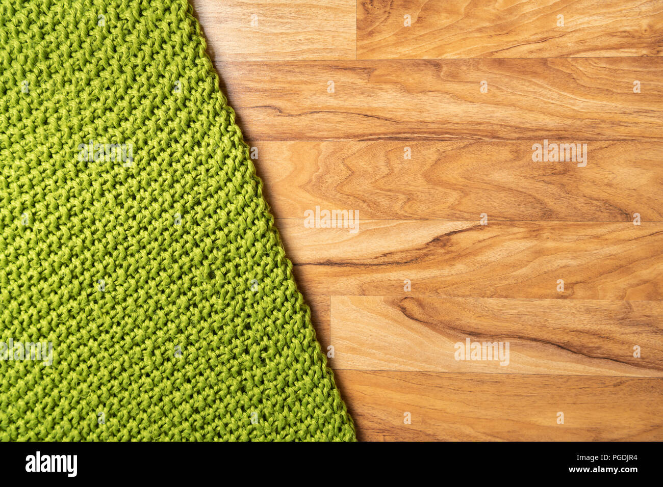 Wolldecke, grün, aus Gewirken große chunky Garn. Nahaufnahme der gestrickte Decke auf Holz- Hintergrund. Stockfoto