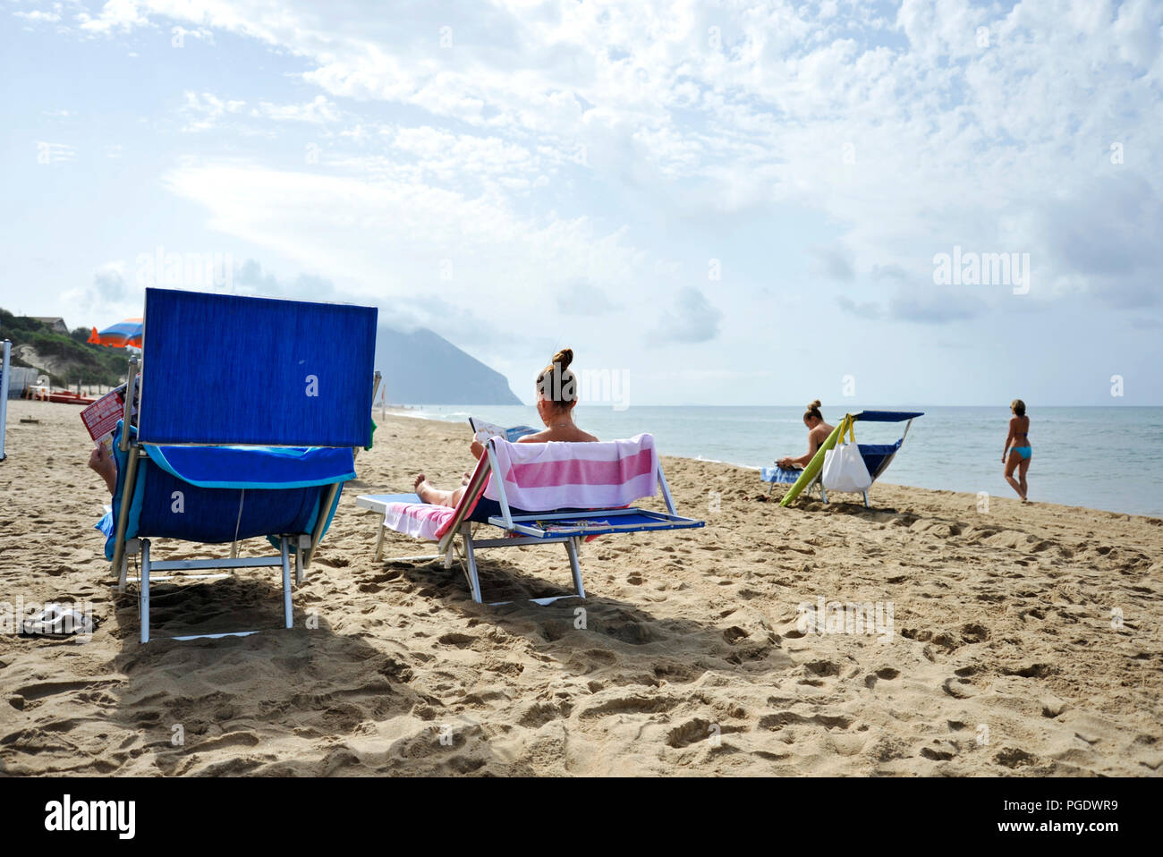 Frauen am Strand entspannen durch Lesen klatsch Zeitschriften. Sabaudia, Latium, Italien Stockfoto