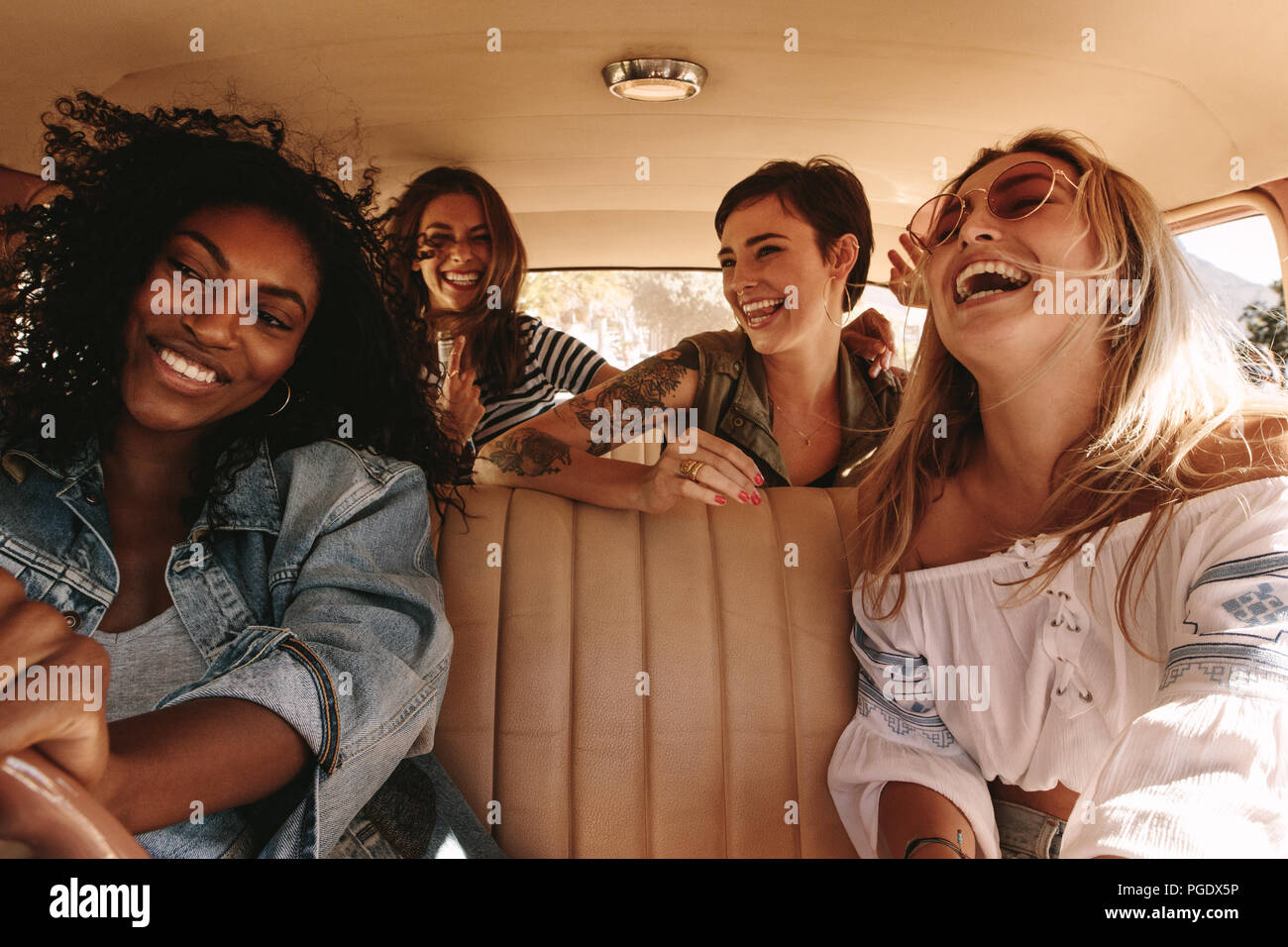 Gruppe von vier Frauen auf einen Road Trip. Multirassischen weibliche Freunde durch ein Auto, Reisen und Genießen. Stockfoto