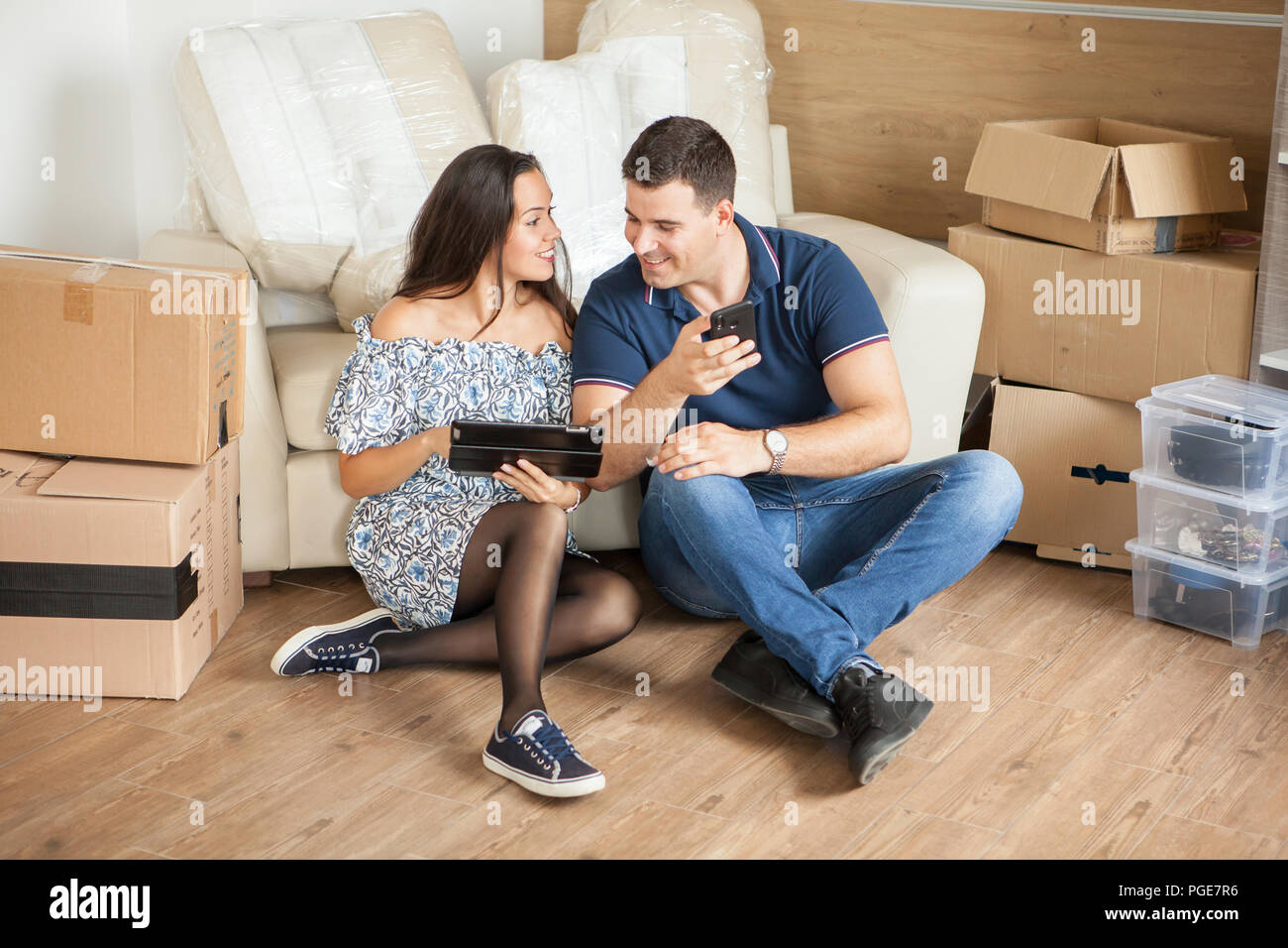 Frau, die ihrem Mann die neuen Vorhänge auf ihrem Tablet-PC. Paar Erstellen von Erinnerungen Stockfoto