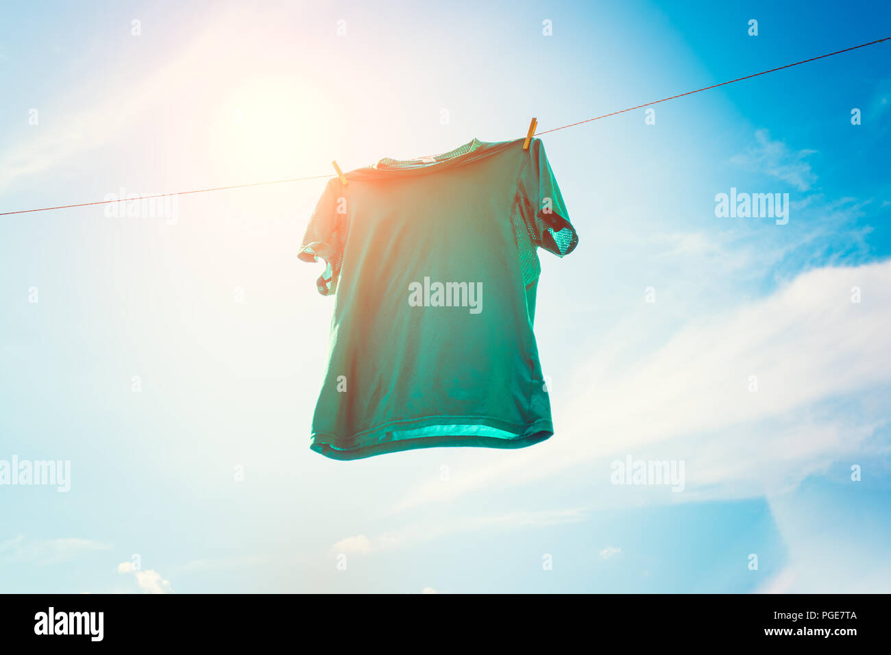 Foto von grünem T-Shirt hängen am Seil gegen den blauen Himmel Hintergrund. Stockfoto