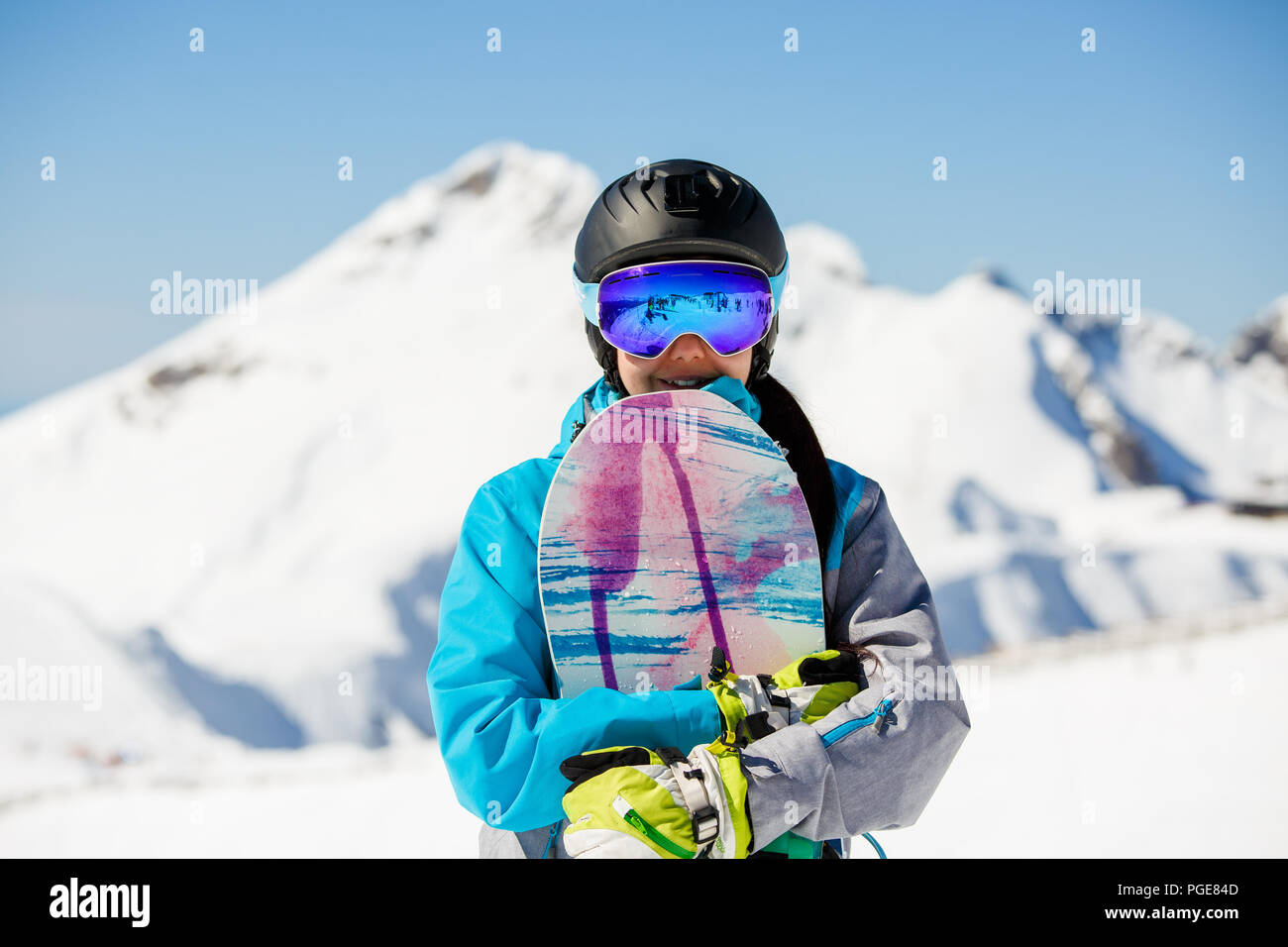 Foto von Frau Helm tragen Sonnenbrillen, mit Snowboard auf dem Hintergrund der Schnee Berge und blauer Himmel Stockfoto