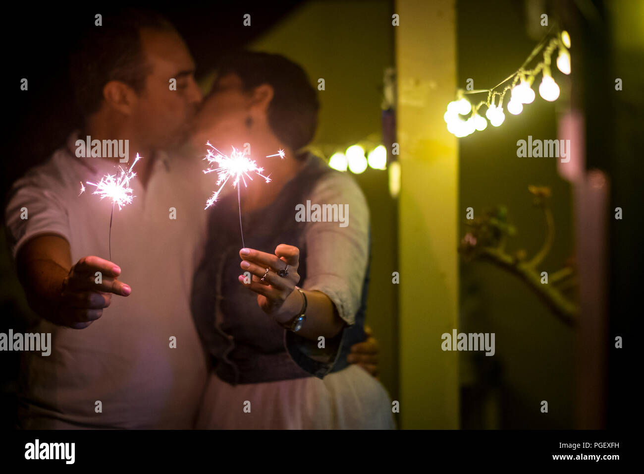 Küssen Liebespaar während einer Party zu Hause feiern mit funkelt Licht. Zärtlichkeit und Glück für immer Konzept. Fokus auf Feuer und Mann und Wom Stockfoto