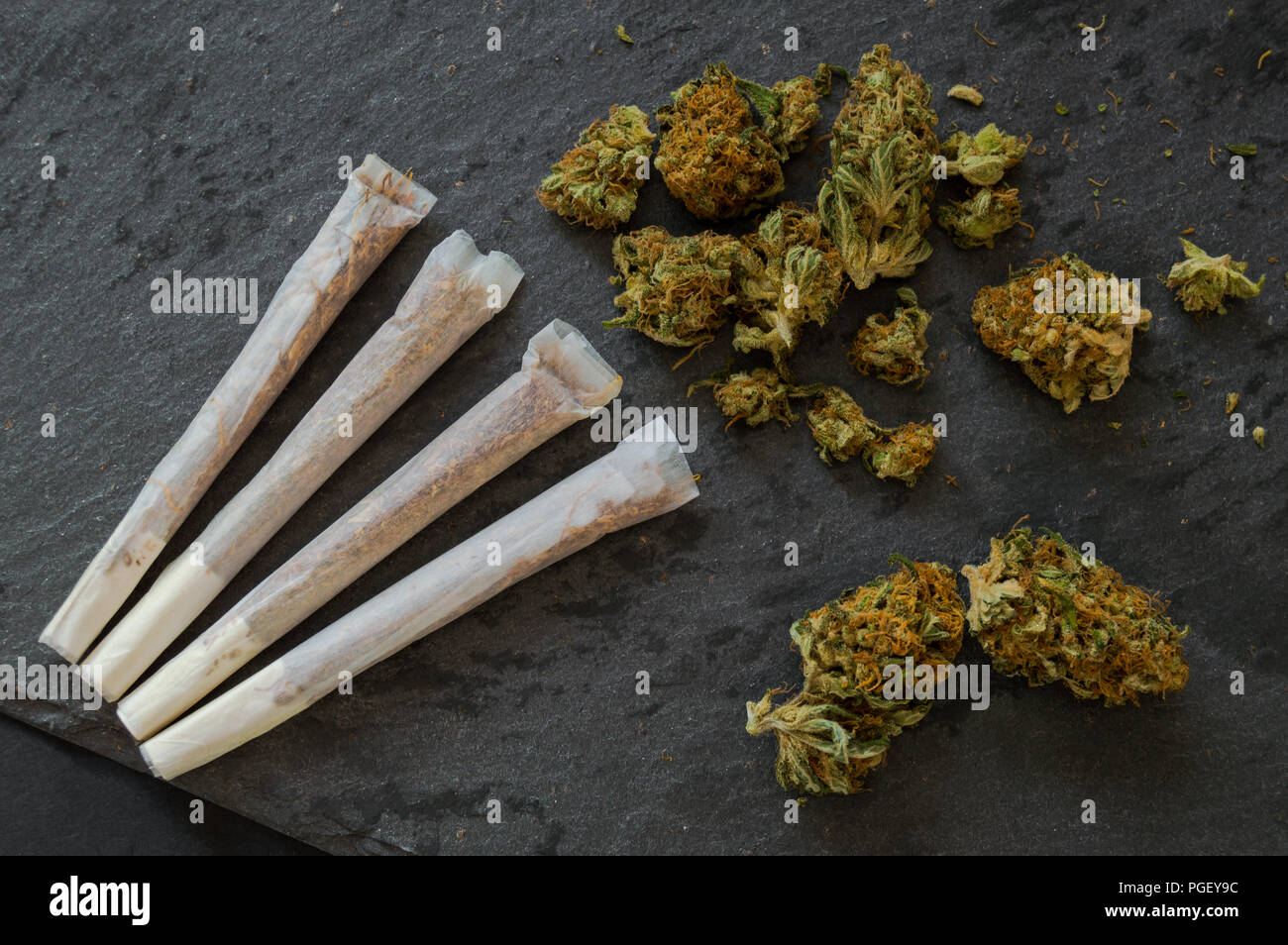 Marihuana Gelenke bereit zu rauchen und einen Haufen Unkraut Knospen auf schwarzen Steintisch. Nahaufnahme Hintergrund mit Droge details. Stockfoto