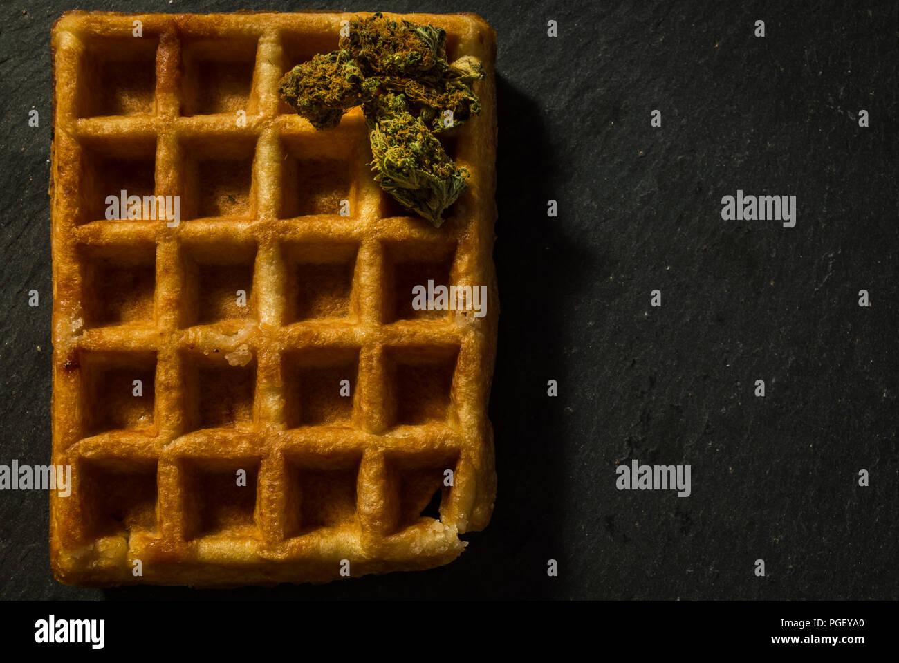 Süße Waffel mit etwas Marihuana Knospen auf. Unkraut und Süßigkeiten, Knabbereien zu nach dem Rauchen befriedigen. Hintergrund der schwarzen Stein. Kopieren Raum rechts. Stockfoto