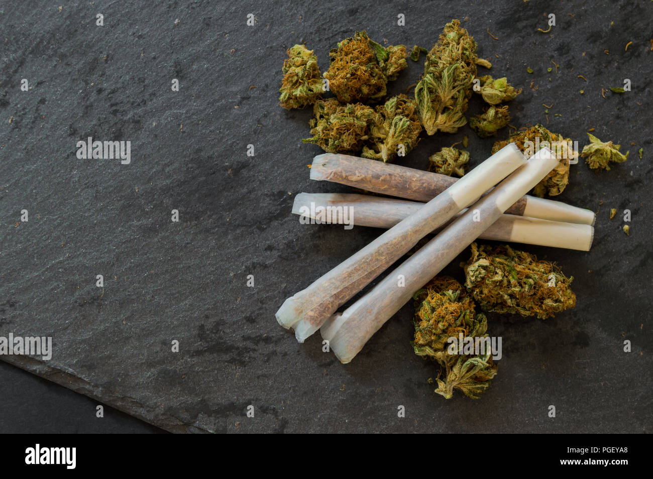Marihuana Gelenke bereit zu rauchen und einen Haufen Unkraut Knospen auf schwarzen Steintisch. Nahaufnahme Hintergrund mit Droge details. Kopieren Sie Speicherplatz frei ist. Stockfoto