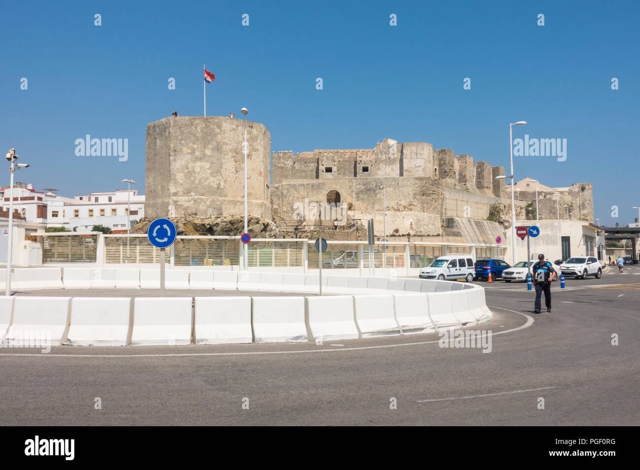 Tarifa Spanien. Kreisverkehr und Einfahrt zum Hafen von Tarifa, dahinter Schloss Guzman El Bueno, Andalusien, Spanien. Stockfoto