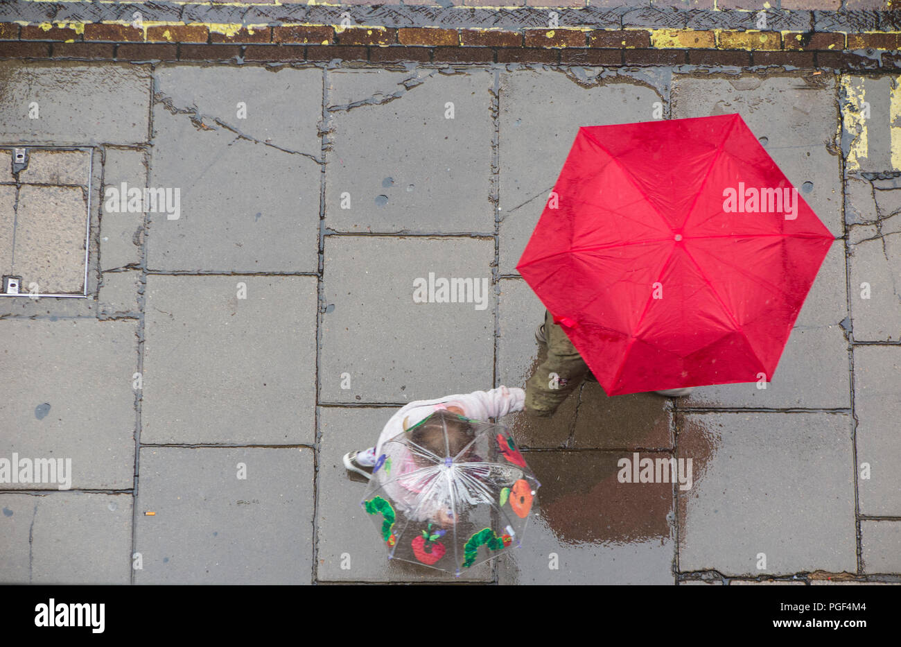 Regen- und Sonnenschirme werden angehoben, trocken auf einer Londoner Straße zu halten - eine Mutter und Kind Hände mit einem Regenschirm Stockfoto