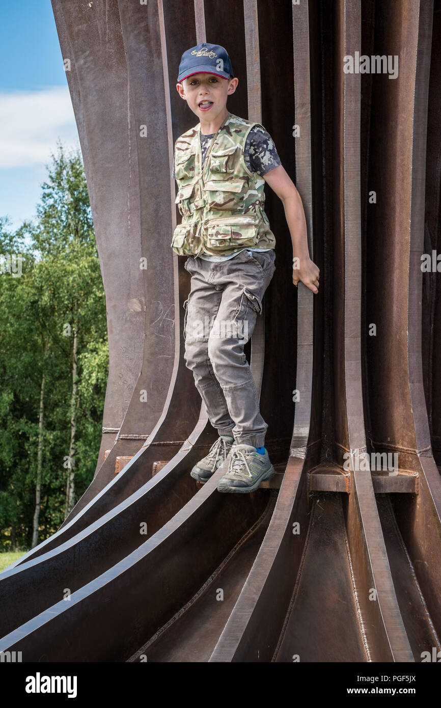 Neun Jahre alten Jungen auf den Stufen der Engel des Nordens Statue, Gateshead, Newcastle, England, Vereinigtes Königreich. Stockfoto