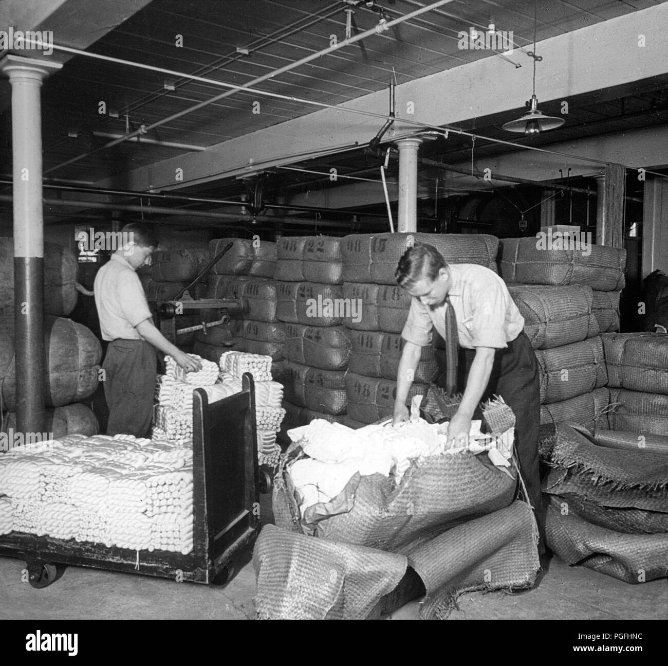 [C. 1900 USA - Seide Industrie] - öffnung Ballen von Rohseide in einem Lagerhaus in Manchester, Connecticut, USA. Grège wurde aus Japan, China und Italien importiert. 20. Jahrhundert vintage Glas schieben. Stockfoto