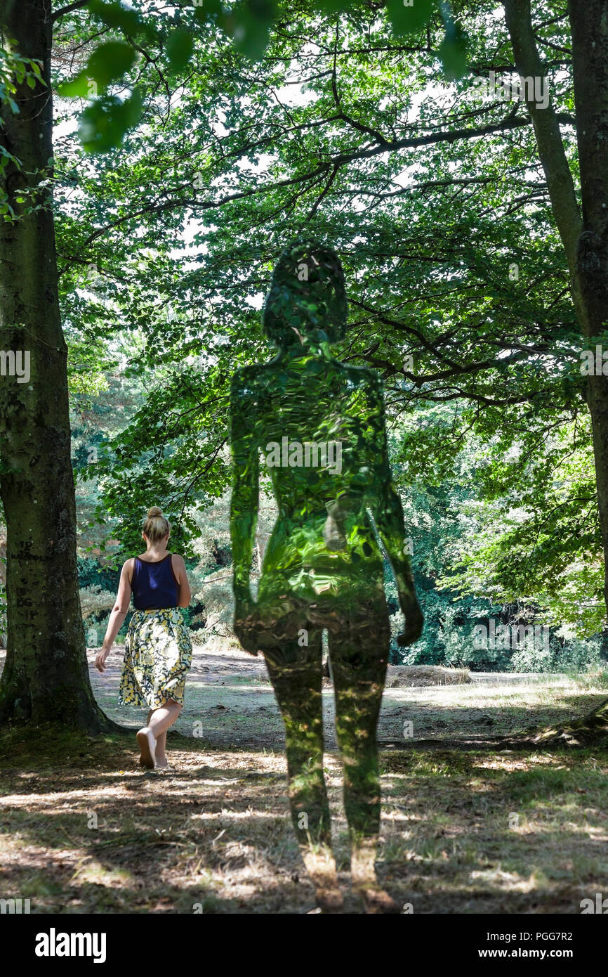 Eine Frau, die an einem der stark reflektierenden "natürliche Schöpfung' Kunst Figuren des Künstlers Rob Mulholland bei niedrigen Kraft, Bowlees, County Durham erstellt, Stockfoto