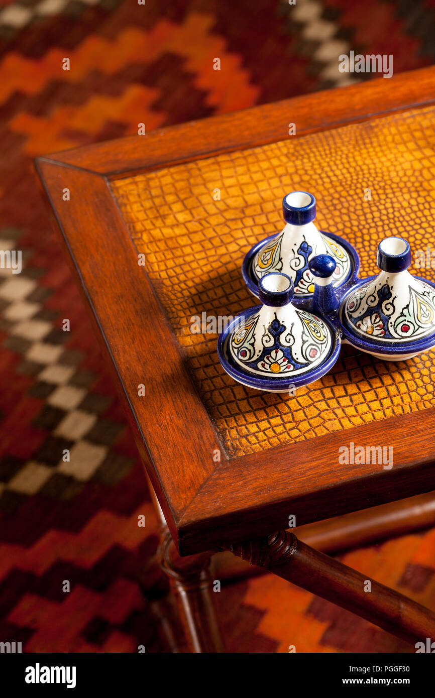 Bunte marokkanische Keramik-Accessoires auf einem Beistelltisch mit einem Kelim-Teppich im Hintergrund. Inneneinrichtung Stockfoto