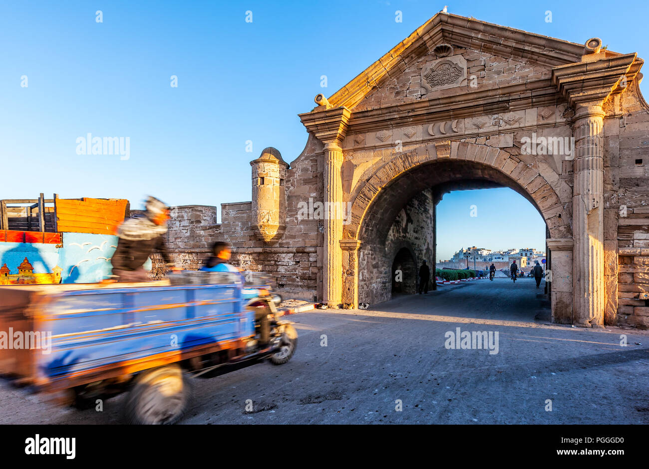 Marokko gateway zu Essaouuira. Beschleunigung Warenkorb mit Motion blur Laufwerke, die mit dem schönen gewölbten Öffnung der alten Befestigungsmauer der Stadt am Meer. Stockfoto