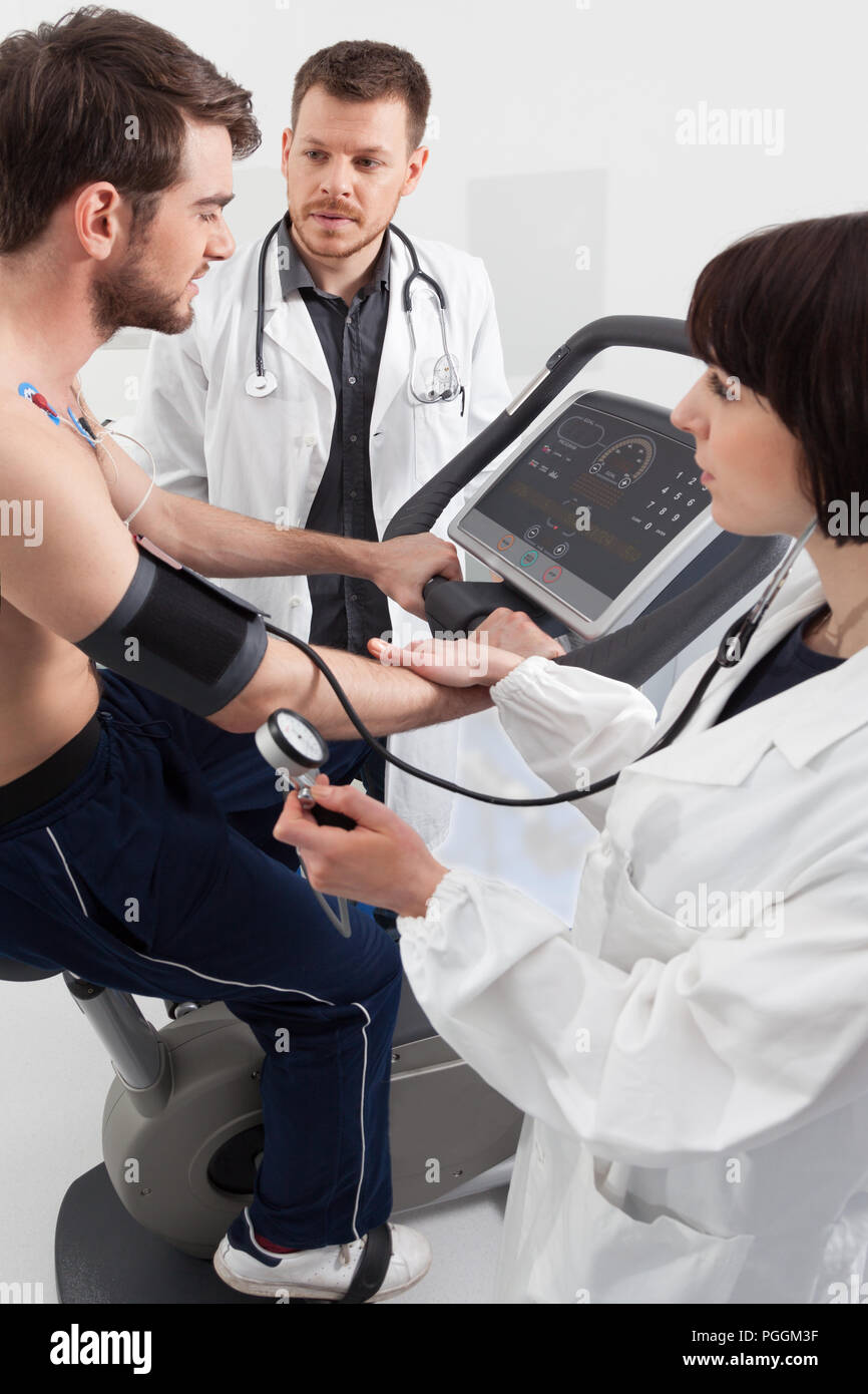 Ein männlicher Patient, radeln auf einem Fahrradergometer Belastungsprobe für die Funktion seines Herzens überprüft Stockfoto