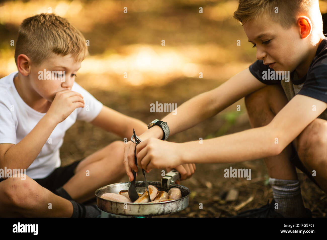 Jungen kochen auf Camping Herd im Freien Stockfoto