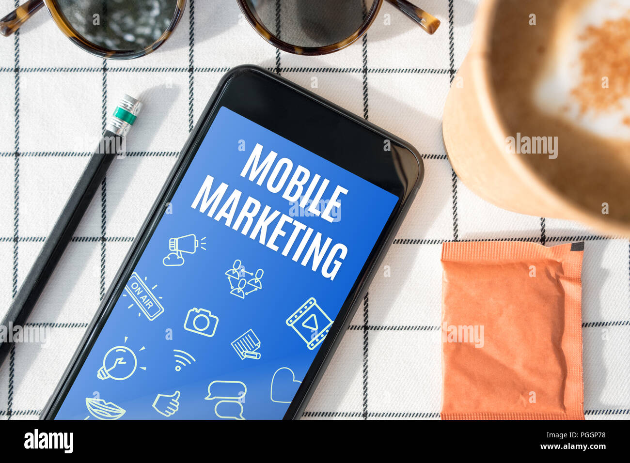 Ansicht von oben Mobile Marketing Feature auf mobilen Bildschirm mit Kaffeetasse, Sonnenbrille, Bleistift auf weiße Tischtuch. digitale Werbung Stockfoto Ansicht von oben Mobile Marketing Feature auf mobilen Bildschirm mit Kaffeetasse, Sonnenbrille, Bleistift auf weiße Tischtuch. digitale Werbung Stockfoto