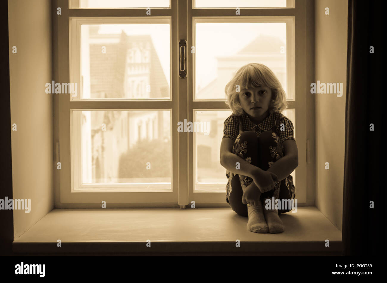Kleine blonde Mädchen allein sitzen Stockfoto