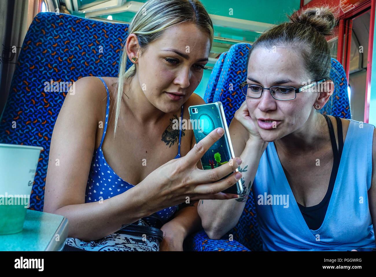 Zwei junge Frauen im Zug schauen sich ihr Smartphone an, Tschechien Stockfoto