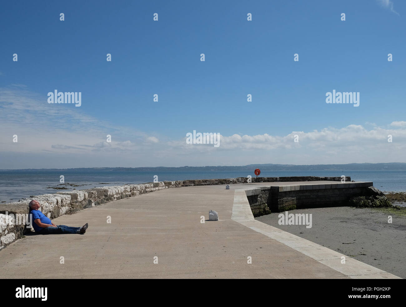 Man Sonnenbaden auf Fishermans' Kai, Antrim, Nordirland. Stockfoto