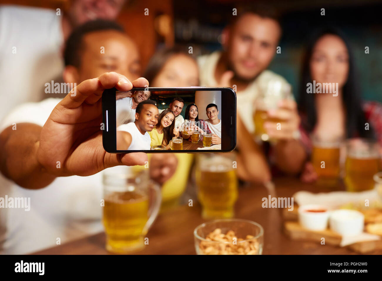 Gruppe der lustige Freunde tragen in Freizeitkleidung, Selbstportrait, lächelnd und trinken Bier in der Bar. Vier Jungs und zwei Mädchen Spaß haben und Genießen Stockfoto