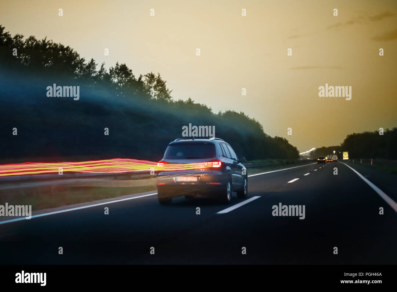 Ansicht der Rückseite des Auto fahren auf der Autobahn bei Sonnenuntergang wit Linien der Rückleuchten. Stockfoto
