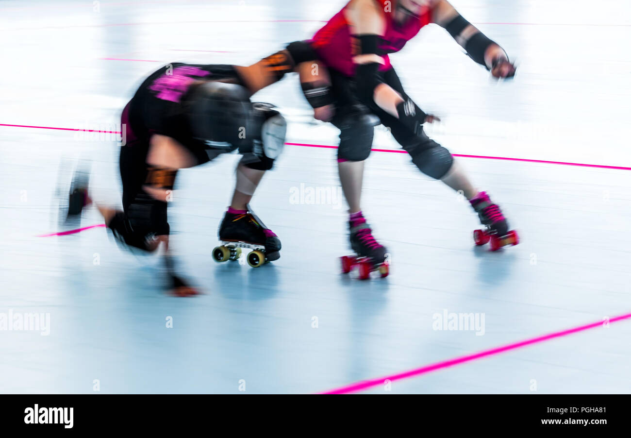 Roller Derby Skater aus der Nähe mit Bewegungsunschärfe. Skater kollidieren, man fällt. Team Wettbewerb. Frauen Stockfoto