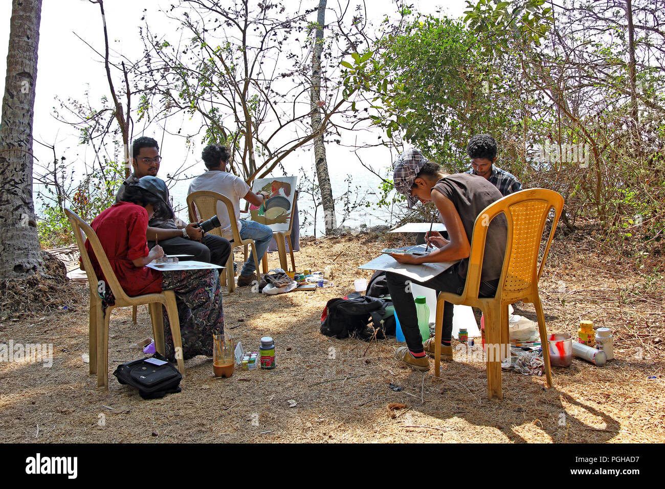 Junge männliche und weibliche Künstler erstellen Gemälde an einem malerischen Strand Park in der Nähe von Siridao Beach in Goa, Indien Stockfoto