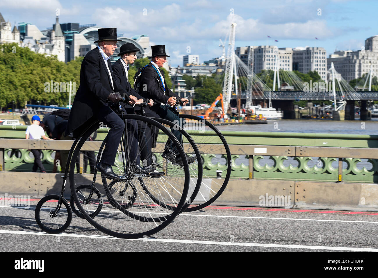 Drei Penny Farthing Radfahrer Fahrt über die Westminster Bridge, London, UK. Herren Reiter. Penny farthings von UDC, Einrad dot com. Top Hüte Stockfoto