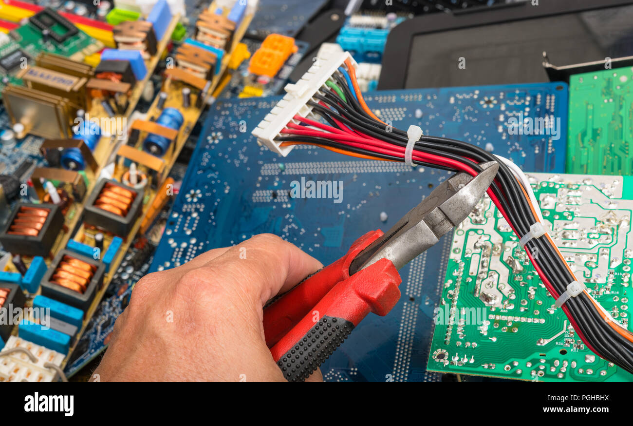 Entsorgung von e-Müll. Hand mit einer Zange. Stecker mit Kabel für Computer Mainboard. Leiterplatten, elektrische PC Teile auf farbigen Hintergrund. Stockfoto