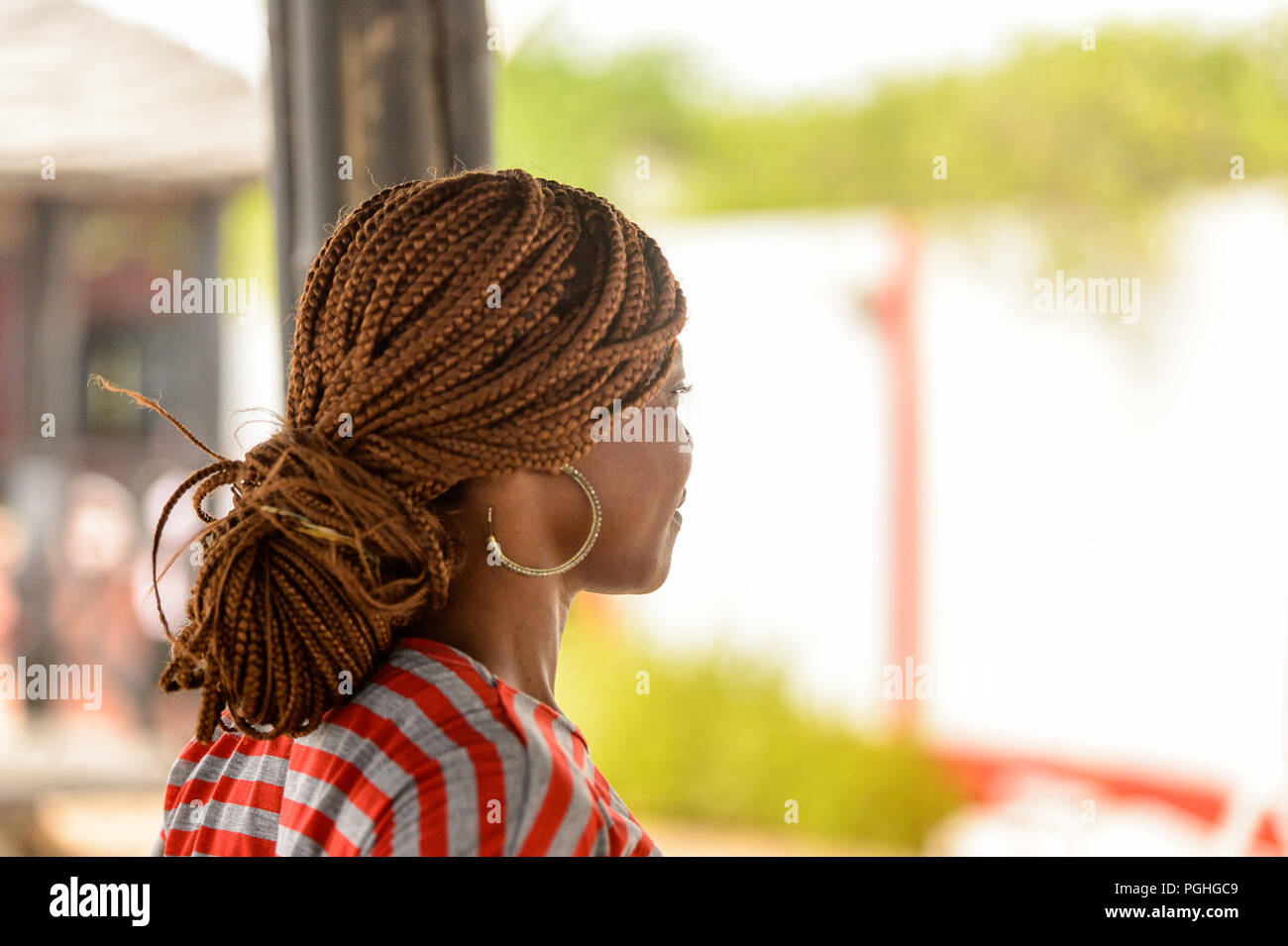 LOME, TOGO - Jan 9, 2017: Unbekannter togoische Frau in farbiges Shirt mit Zöpfen und Big earing. Togo Menschen leiden unter der Armut aufgrund der schlechten Econom Stockfoto