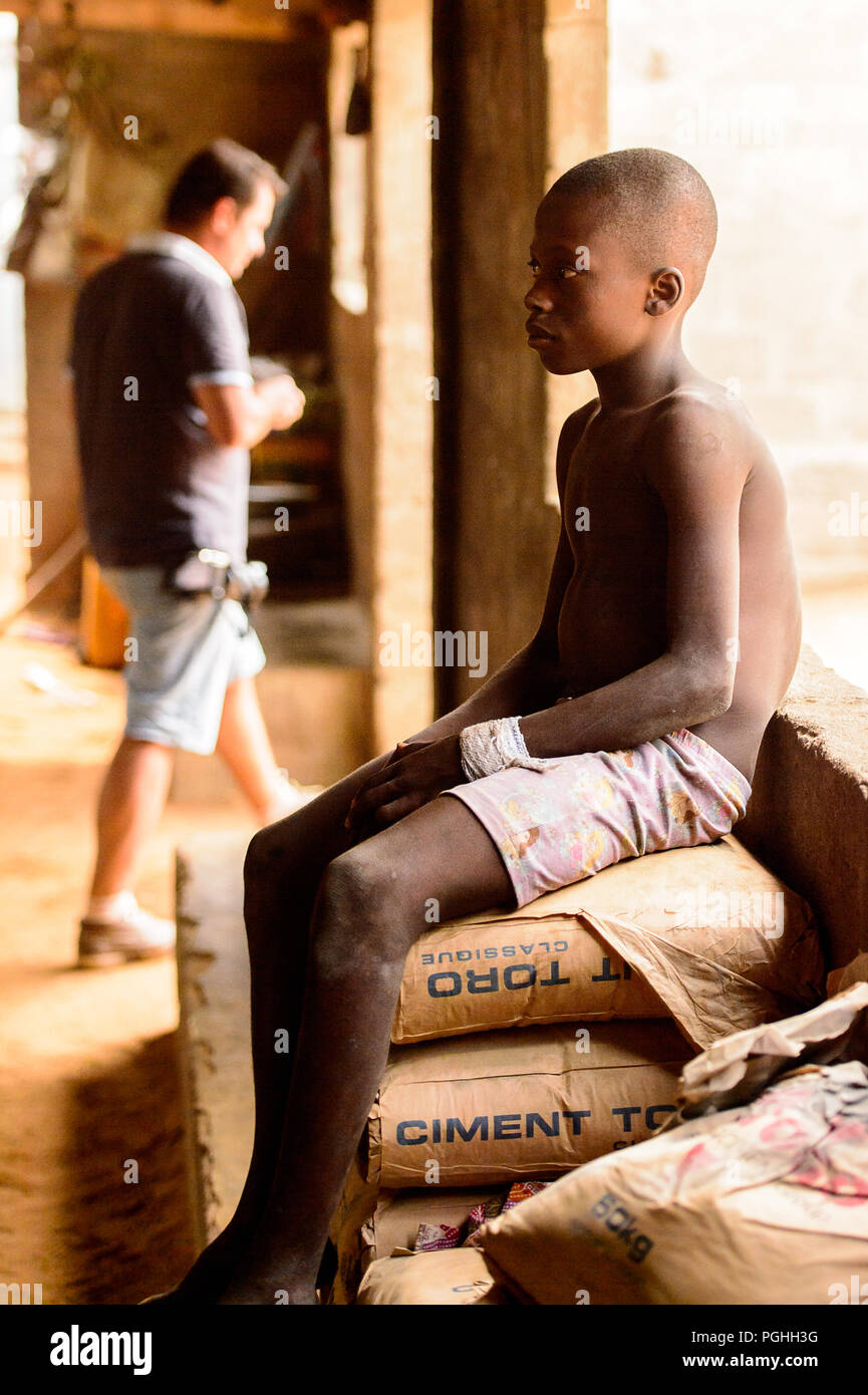 LOME, TOGO - Jan 9, 2017: Unbekannter togoischen Junge sitzt auf dem Zement Tasche im Haus des lokalen Schamanen. Togo Kinder leiden der Armut durch t Stockfoto