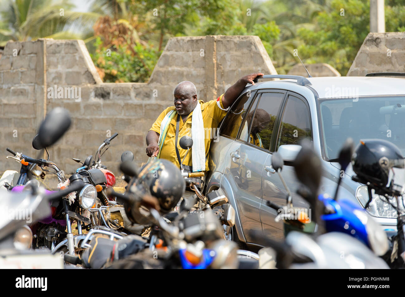 OUIDAH, BENIN - Jan 10, 2017: Unbekannter beninischen Mann lehnt sich an den geparkten Auto. Benin Menschen leiden unter der Armut wegen der schlechten Konjunktur Stockfoto
