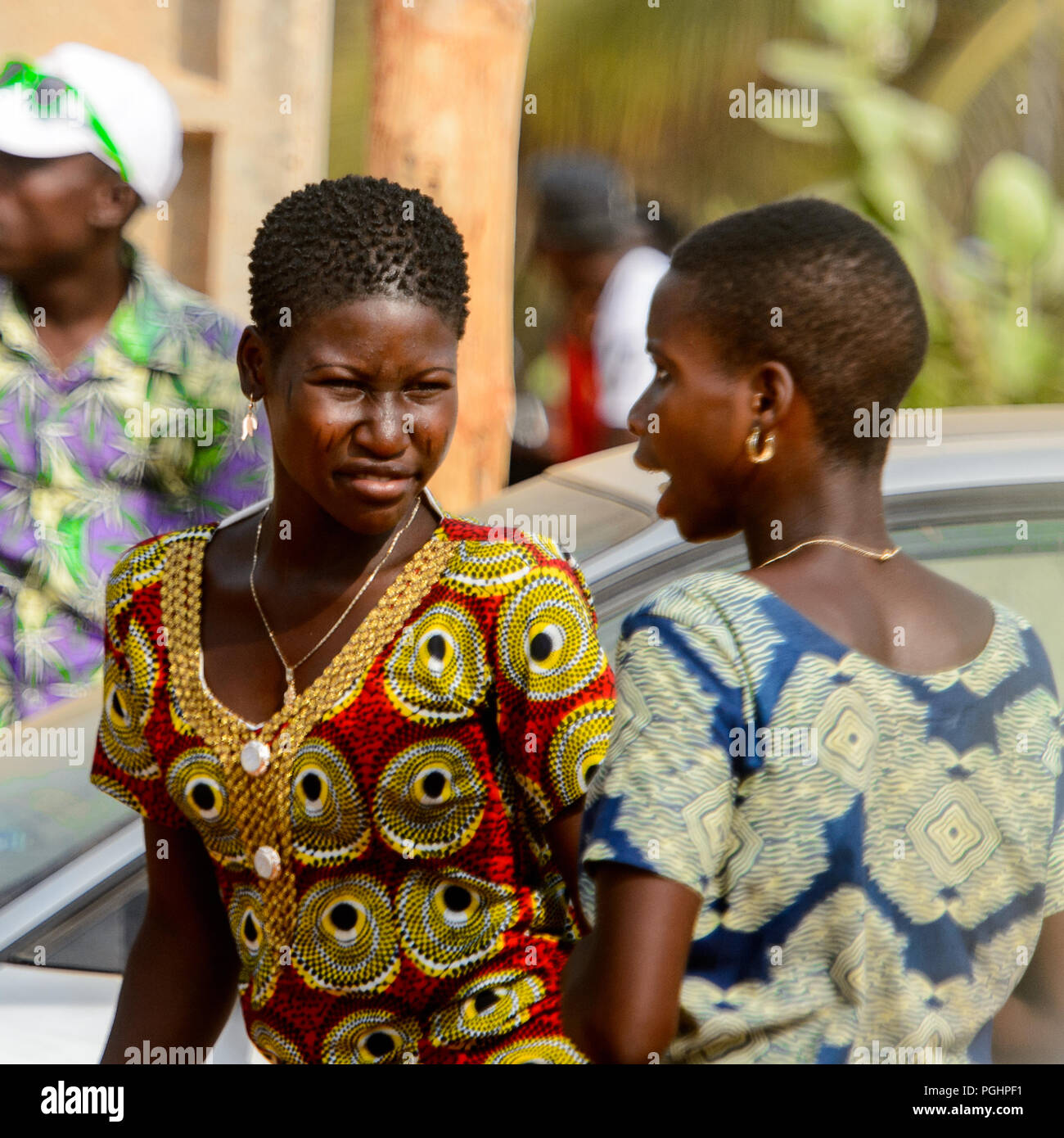 OUIDAH, BENIN - Jan 10, 2017: Unbekannter Beniner Frauen mit kurze Haarschnitte in bunten Kleidern auf der Straße laufen. Benin Menschen leiden unter der Armut du Stockfoto