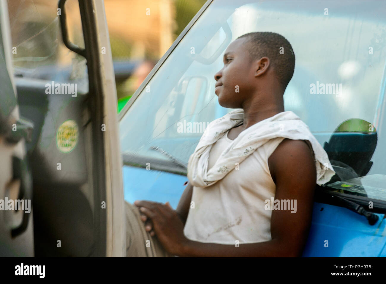 OUIDAH, BENIN - Jan 10, 2017: Unbekannter Beninischen jungen Mann im weißen Hemd lehnt sich an das Auto am lokalen Markt. Benin Menschen leiden unter der Armut durch Stockfoto