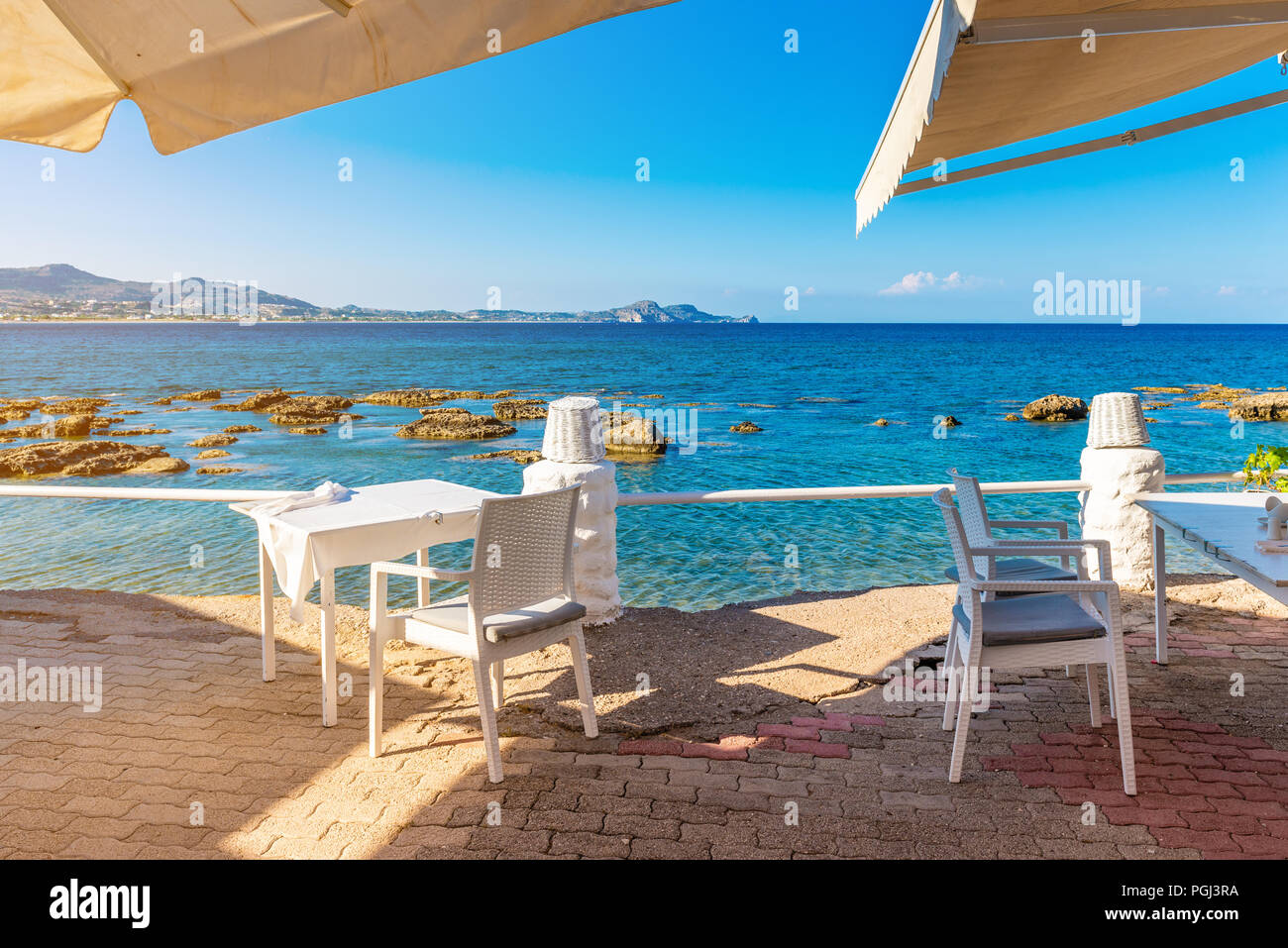 Tisch und Stühle in den Küstengebieten Restaurant am Strand von Kolymbia. Die Insel Rhodos, Griechenland Stockfoto