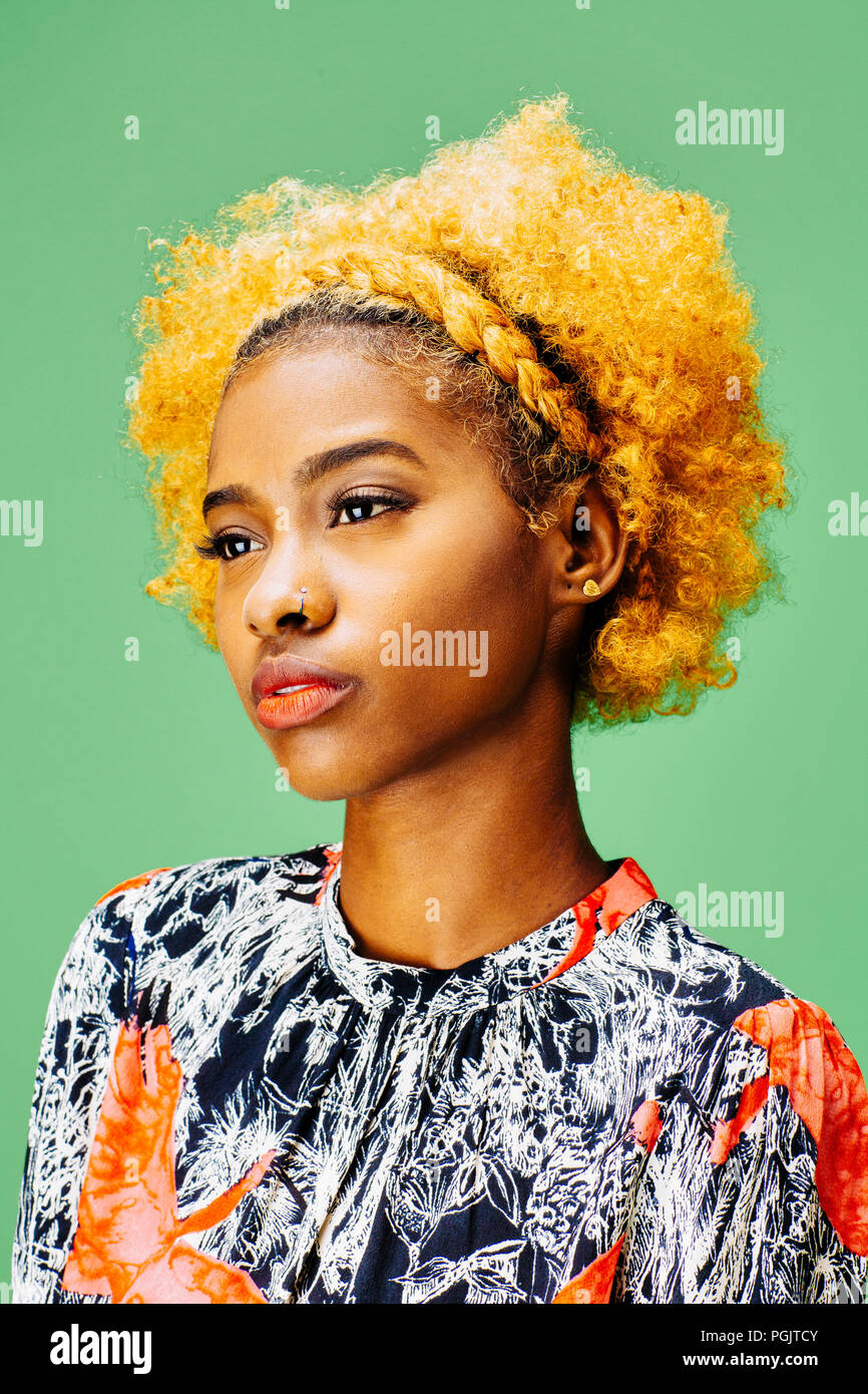 Porträt einer reizenden jungen Mädchen mit lockigem Haar gebleicht, vor einem grünen Hintergrund Stockfoto