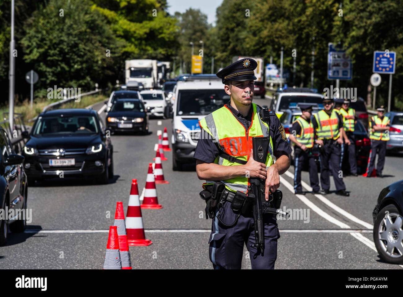 Freilassing, Bayern, Deutschland. 27 Aug, 2018. Ein Schutz der Grenzen Polizisten aus Bayern hält ein Maschinengewehr am Saalbruecke Brücke. Deutsche Innenminister Horst Seehofer und Bayerns Innenminister Joachim Herrmann, Auftritte im Freilassing Saalbruecke Grenzübergang zwischen Deutschland und Österreich zu diskutieren, die Ergebnisse der neu gegründeten Bayerischen Grenzschutzpolizei (Grenzsicherung Polizei). Diese neue Polizei Agentur mit rund 500 Mitarbeitern, wurde am 1. Juli erstellt. Kritiker behaupten, dass Grenzkontrollen ist die Aufgabe der Bundespolizei (Bundespolizei) und nicht eine Aufgabe der Stockfoto