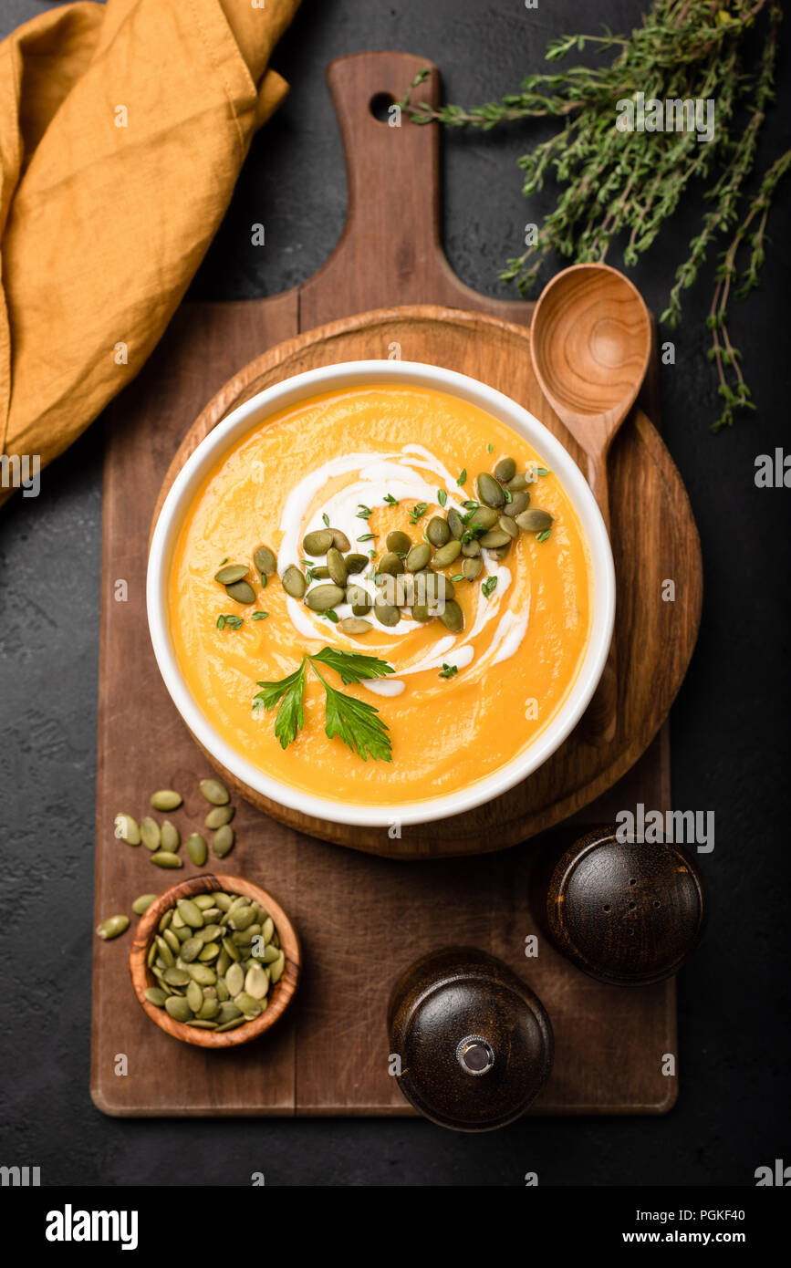 Kürbis Suppe in der Schüssel, garniert mit Sahne und Kürbiskernen. Ansicht von oben. Herbst Herbst Komfort Essen. Creme von Kürbis Kürbis Suppe Stockfoto