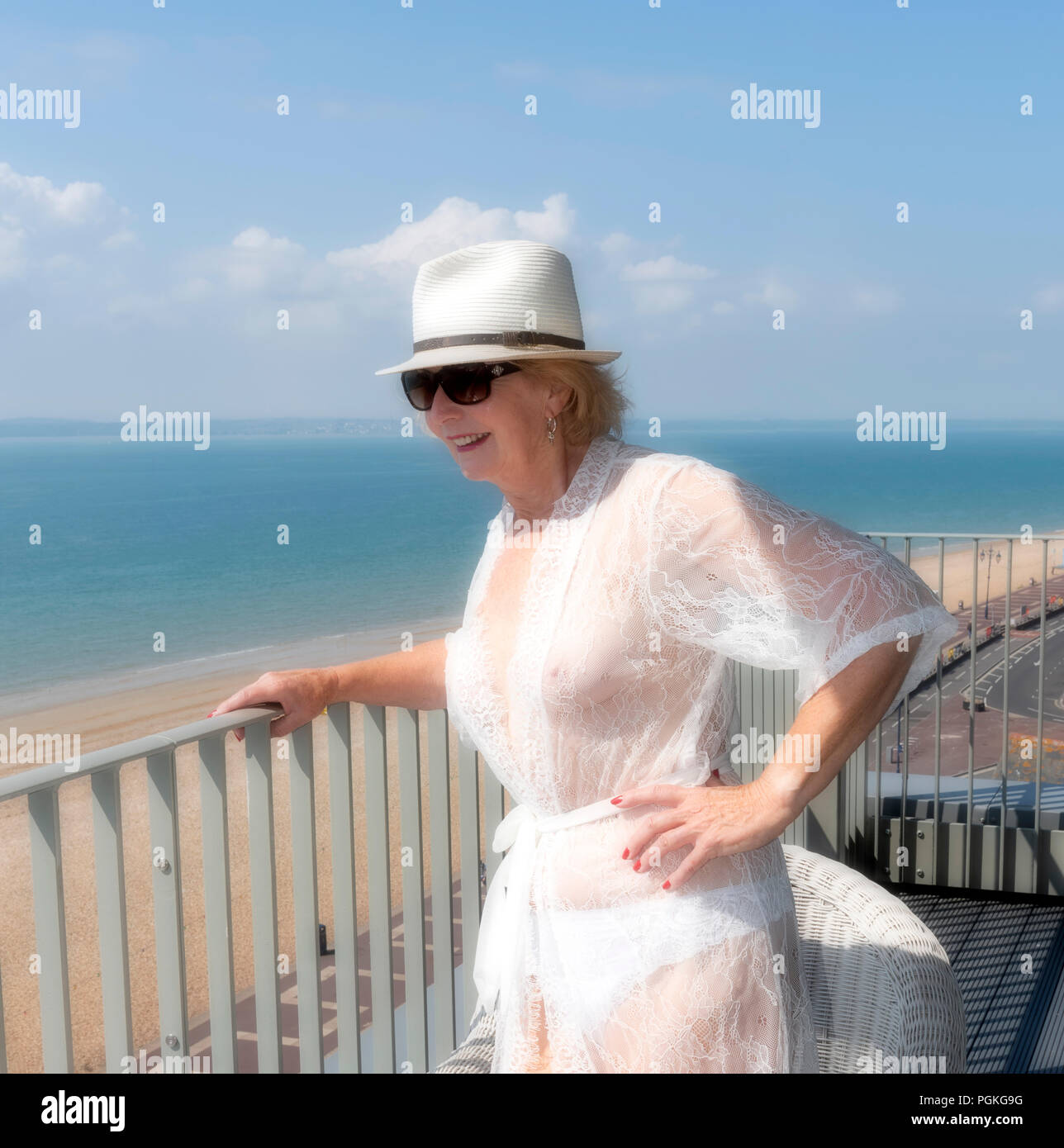 Ältere Frau, die auf einen Balkon am Meer. Southern England Großbritannien Stockfoto