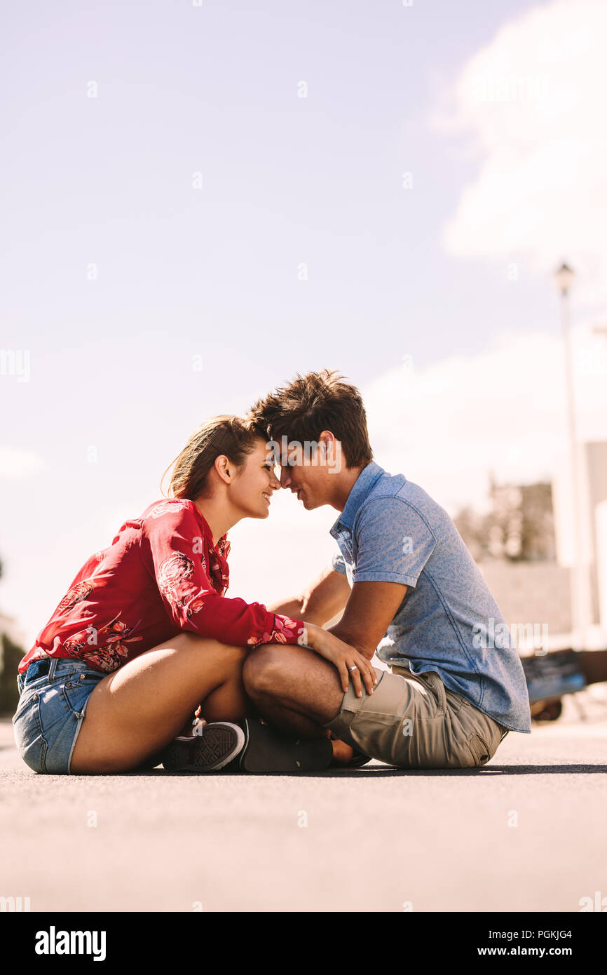 Romantisches Paar sitzen auf dem Boden zusammen, die ihre Köpfe zu berühren. Mann und Frau sitzt auf der Straße gegenseitig berühren ihre Stirn. Stockfoto