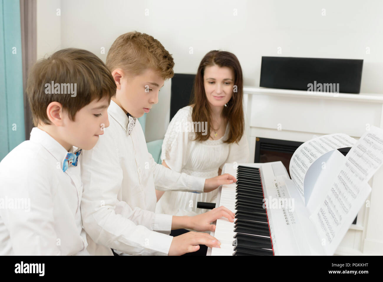 Kinder studieren an e-piano Instrument, spielen im Tandem, Lehrer neben Ihnen Stockfoto