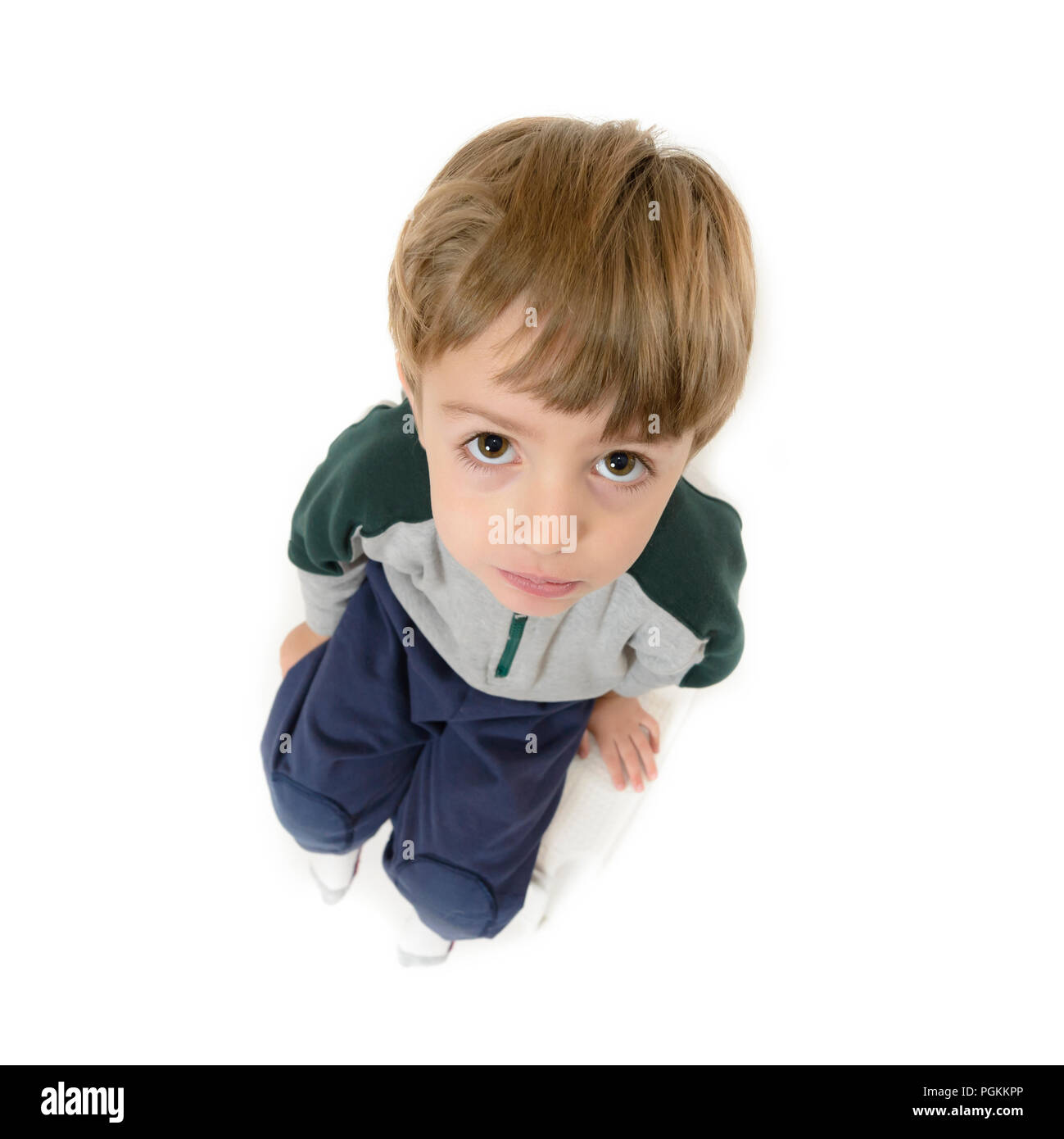 Süße Lonely Boy auf einem Stuhl und sah hilflos, auf weissem isoliert Stockfoto