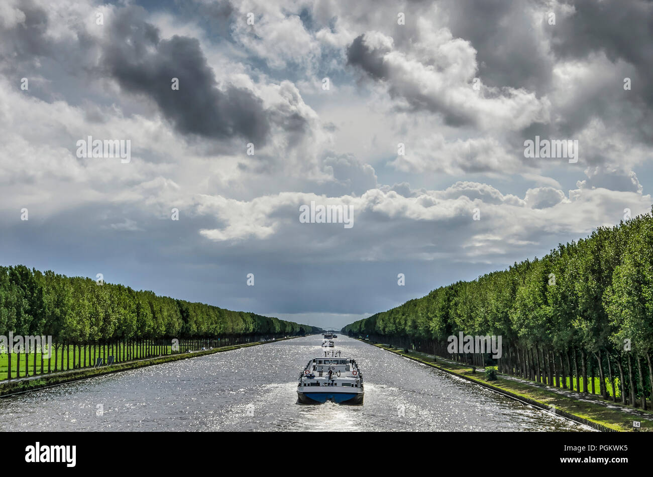Zentrale Perspektive der langen und geraden Amsterdam-Rhein-Kanal südlich von Amsterdam, mit Lastkähnen und lange Linien der Bäume unter einer Dramati Stockfoto