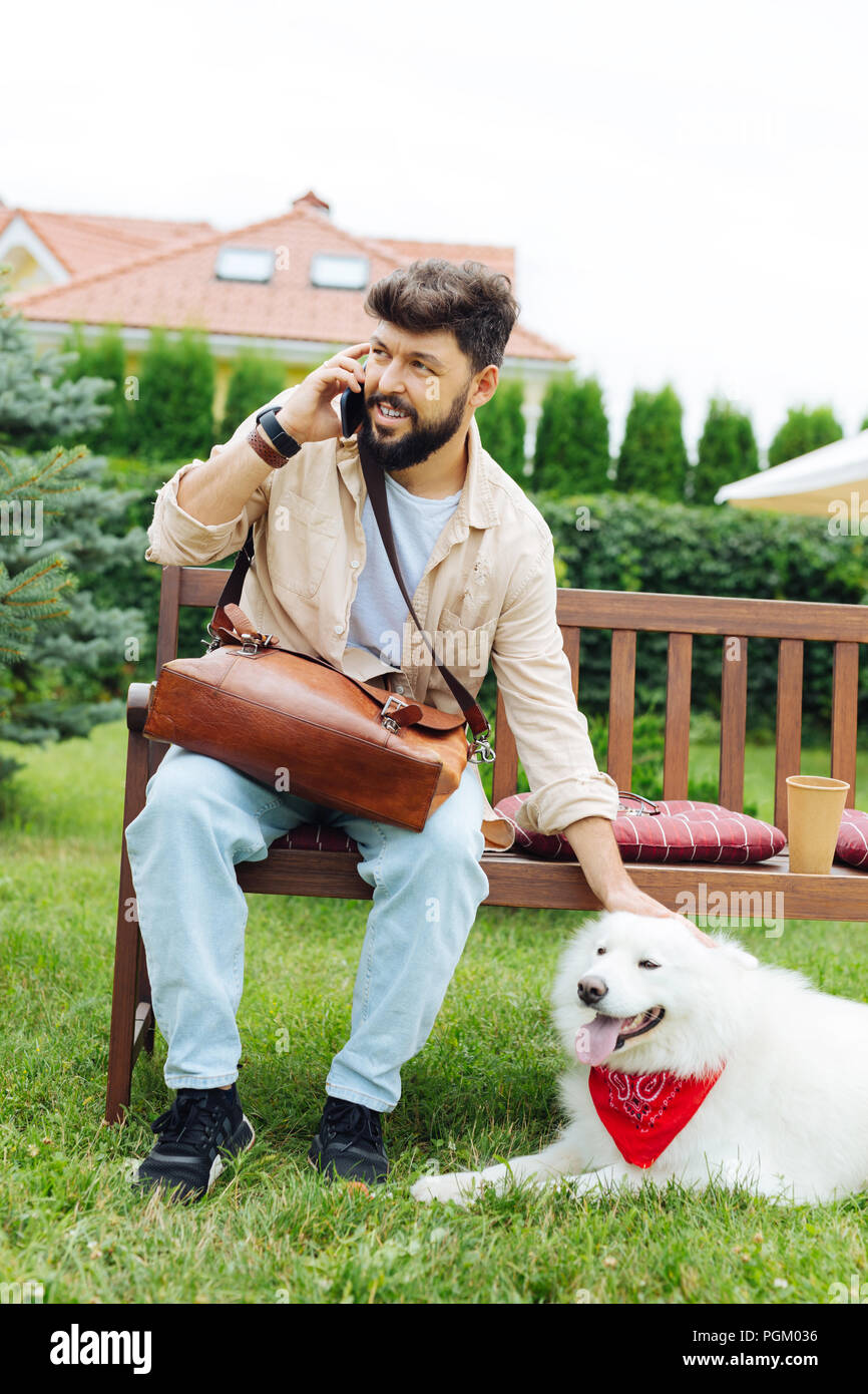 Stilvolle dunkelhaarigen Mann petting seine niedlichen weißen Husky Stockfoto