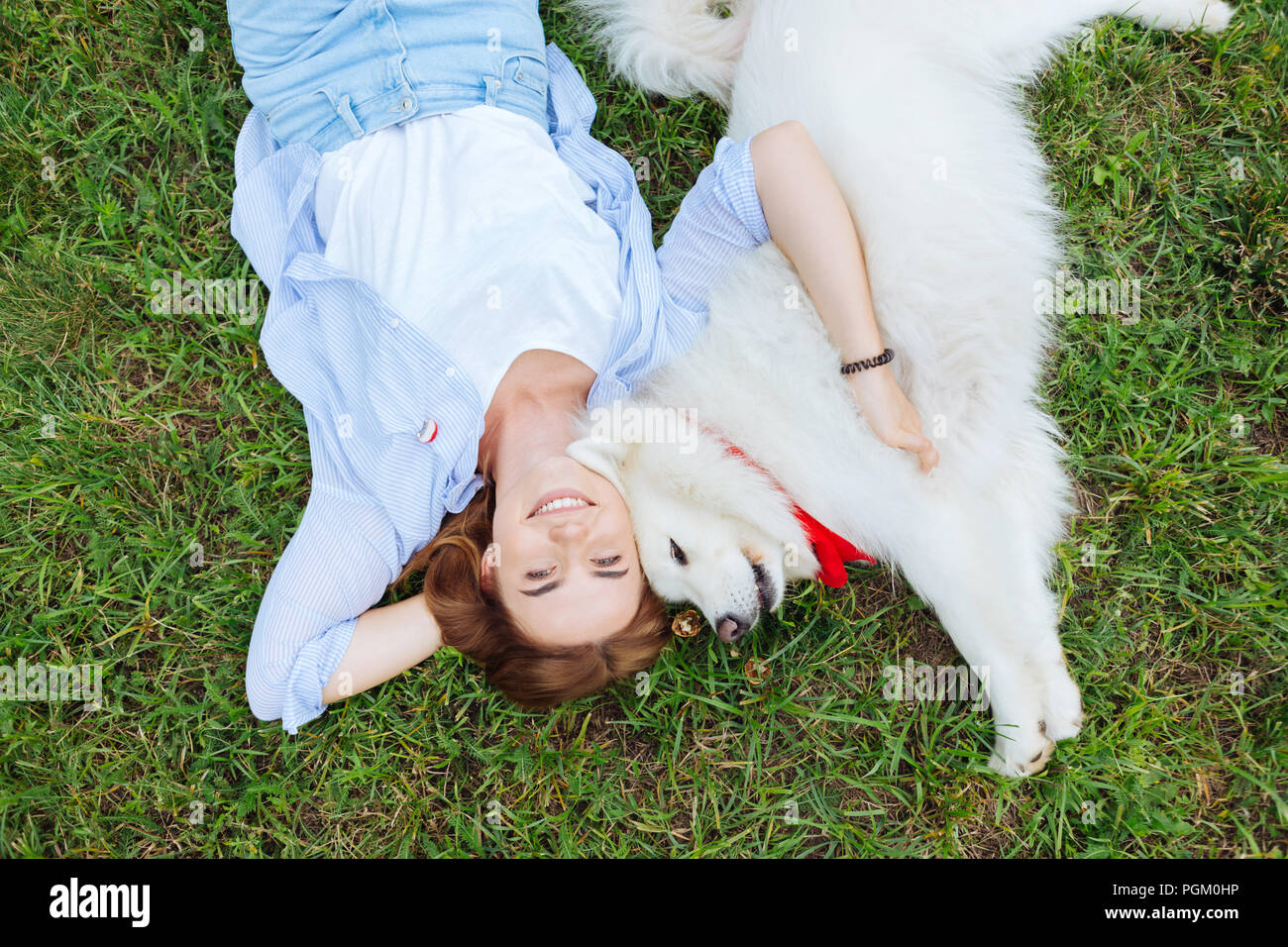 Frau in Jeans und gestreiften Hemd ihre weißen Husky umarmen Stockfoto