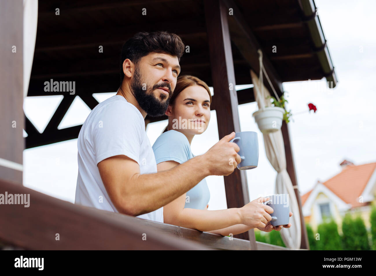 Junge paar hält Blau Becher mit Kaffee stehen auf Balkon Stockfoto