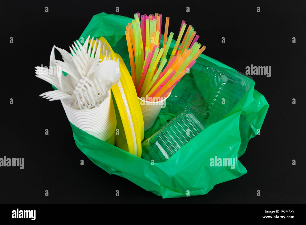 Kunststoffabfälle Gefahr ökologie Konzept mit vollem Müllsack und bunten einzelne strohhalme mit Besteck Tassen Teller Auflauf Boxen isoliert auf Schwarz backgr Stockfoto