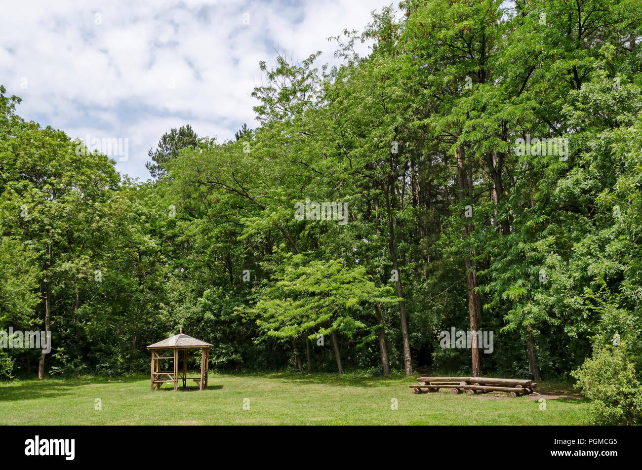 Holzbank, Alkoven und Tabelle auf einer Wiese im Wald an natürlichen Old West Park, Sofia, Bulgarien Stockfoto