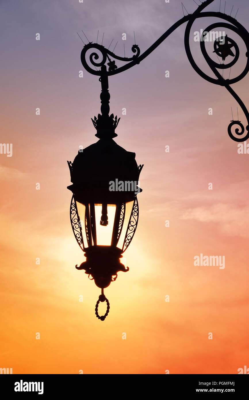 Schließen Sie die Seitenansicht des alten Vintage antik Straße Lampe Laterne, die über helle Abendsonne und lebendige Sonnenuntergang Himmel Stockfoto