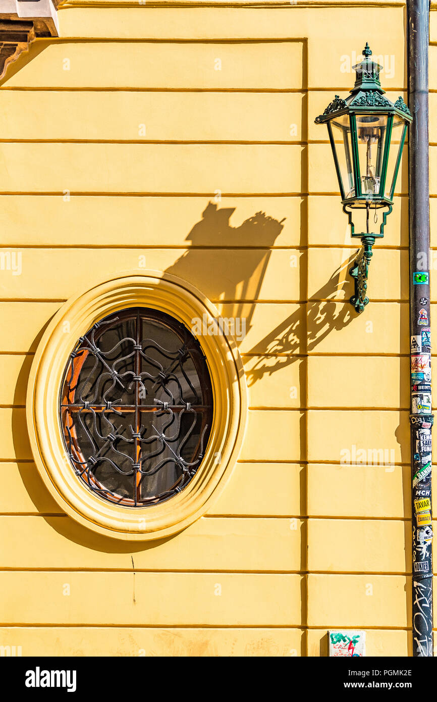 Eine ikonische Lampe und ein ovales Fenster an einer gelben Gebäudefassade im Stadtzentrum von Prag, Tschechien Stockfoto